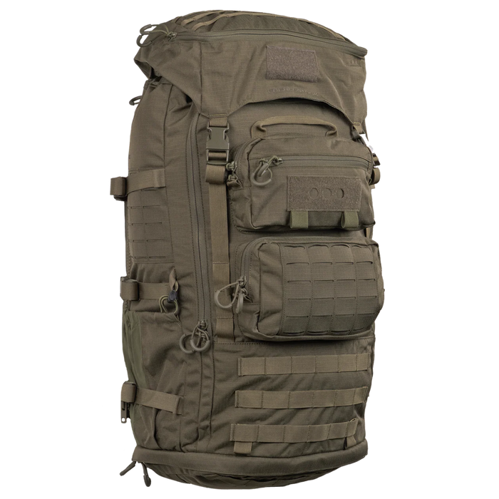 A frontal, slightly angled view of the green Eberlestock Military Pack, showcasing its durable exterior, U-shaped front access zipper, and tactical webbing.