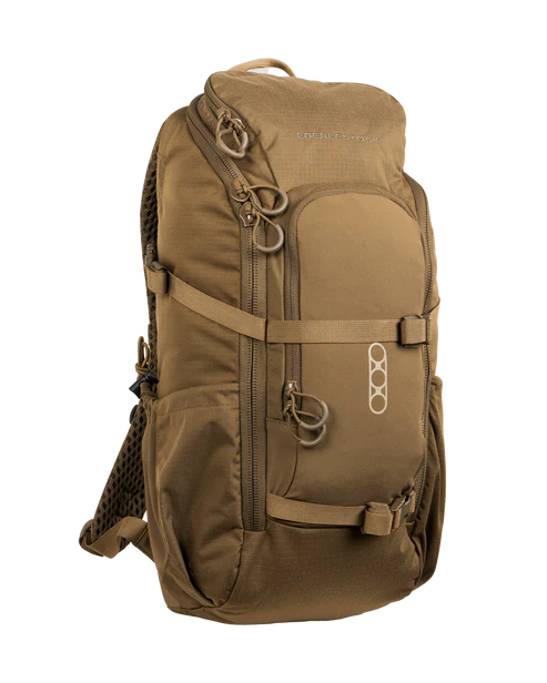 A frontal right-angled view of the Eberlestock Brute Scout Pack in Coyote Brown, emphasizing the tactical storage layout and the water-repellent finish of the 500D nylon exterior designed for harsh field conditions.
