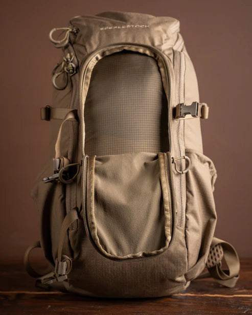 A clear frontal shot of the Brute Scout Hunting Pack with the exterior stretch compartment pulled open, revealing the versatile storage space available for rapid-access gear like rain shells or optics while maintaining a slim profile.
