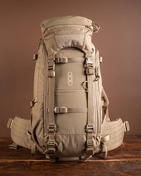 A direct frontal view of the Eberlestock Brute 3500 Weekend Pack in Dry Earth, showing the vertical compression straps and the organized external storage pockets designed for quick access during a hunt.