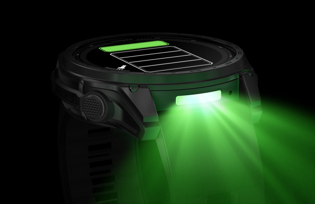 A close-up view of the Garmin tactix 8 solar elite with its built-in multicolor LED flashlight activated in a dimmable green light mode. This specialized tactical feature is designed for stealthy operations under night vision goggles or in dark environments without compromising position security.