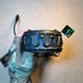 A gloved hand displays the top of a black rubberized headband belonging to a Peltor ComTac VIII tactical headset, highlighting the flexible, ventilated cutout design and 3M branding against a textured tan surface.
