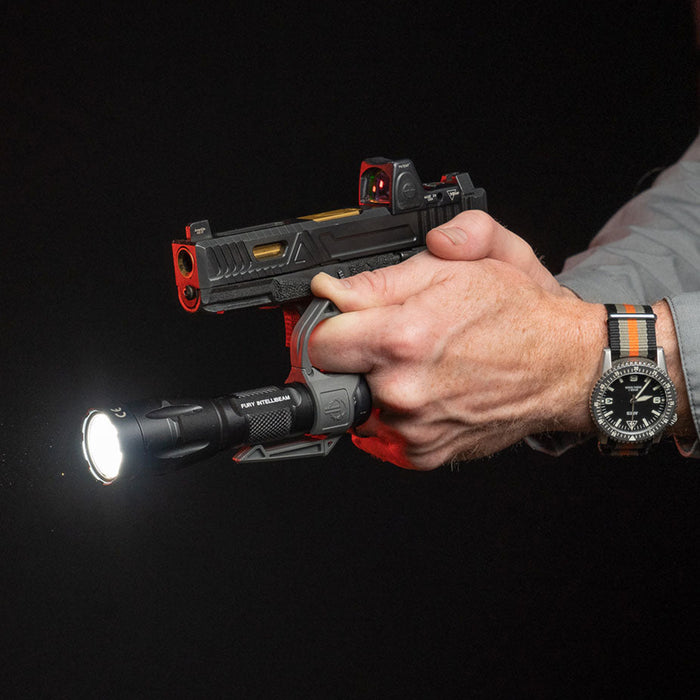 Hand holding a pistol and a tactical flashlight with a SwitchBack 2 ring attachment.
