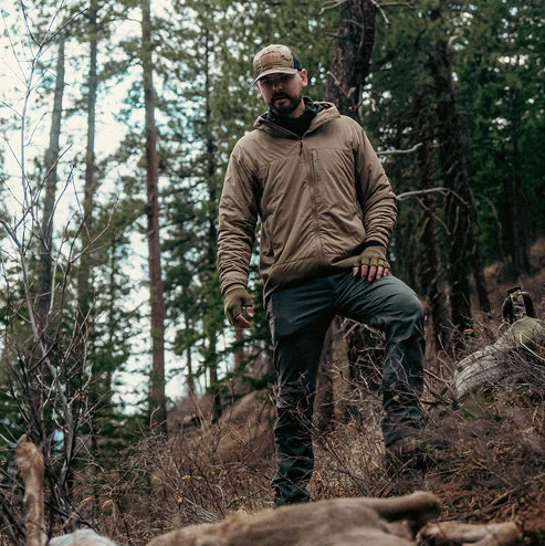 Hunter examining a harvested deer while wearing the Eberlestock Alturas Hooded Jacket in Dry Earth.