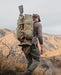 A hunter traversing the field with the Mainframe II Pack Frame, configured with Batwing pouches and a secured rifle for a streamlined, high-mobility scouting loadout.