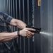 Law enforcement officer clearing an area, peeking around the corner of a container using the SureFire XC3 WeaponLight.