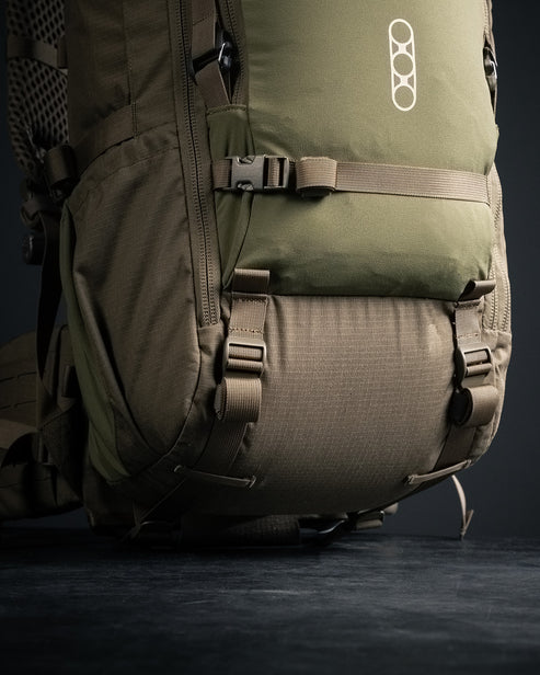 A lower-angle shot of the Brute 4500 Rucksack, detailing the heavy-duty side compression straps and reinforced webbing used to secure external gear and stabilize the load during technical movements.