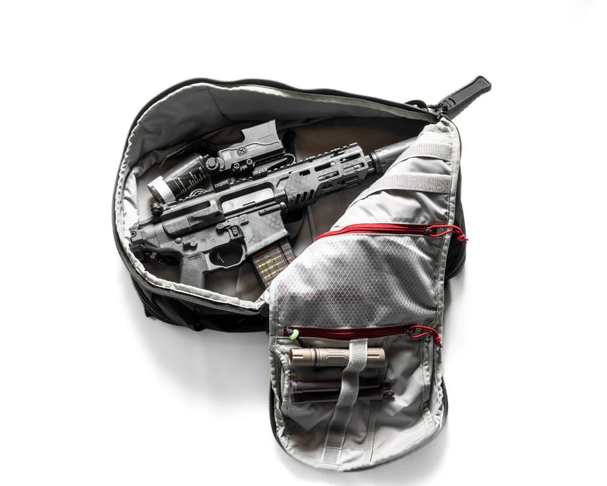 The main compartment of the Vertx Gamut 22L Sling Bag opened to reveal a submachine gun and muzzle device secured inside, demonstrating the bag's superior capacity for specialized tactical loadouts.
