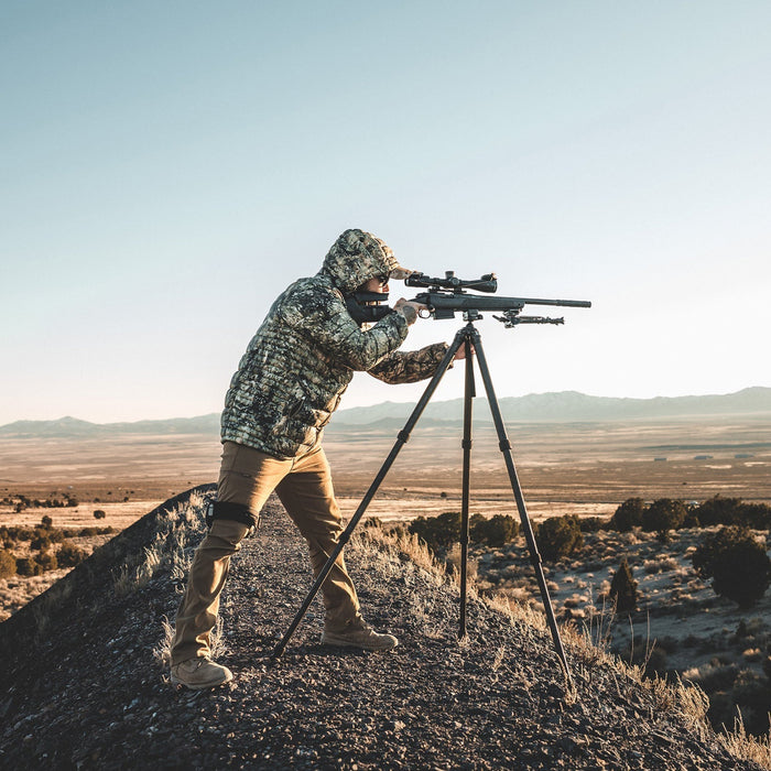 man-aiming-a-tripod-mounted-rifle-wearing-skye-eberlestock-mccall-hooded-down-jacket