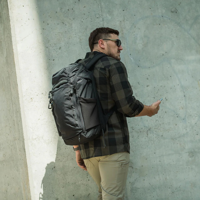 A model showcasing the casual, discreet appearance of the Vertx Gamut 32L Pack, highlighting its low-visibility urban aesthetic that blends seamlessly into daily environments.