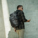 A model showcasing the casual, discreet appearance of the Vertx Gamut 32L Pack, highlighting its low-visibility urban aesthetic that blends seamlessly into daily environments.