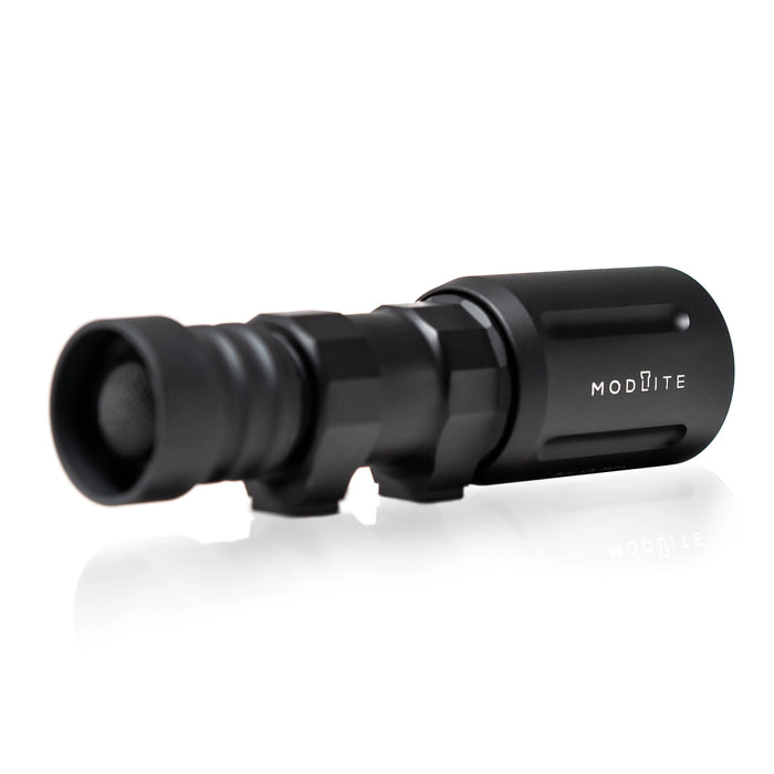 An image of the modlite plhv3 18350 rifle light with rifle attachments placed on the flashlight body and is on the back isometric view and showcasing the black tactical flashlight  in the middle of the photo and with a textured grip and white product lettering detailing its dual fuel, multi-mode capabilities on a reflective surface.