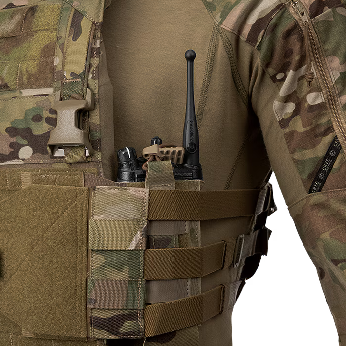 A close-up view of an operator wearing a tactical vest featuring the MultiCam LPV Side Radio Pouch mounted on the side straps. The pouch securely holds a black communication radio, demonstrating its versatile design that can accommodate a radio or M4 mag.