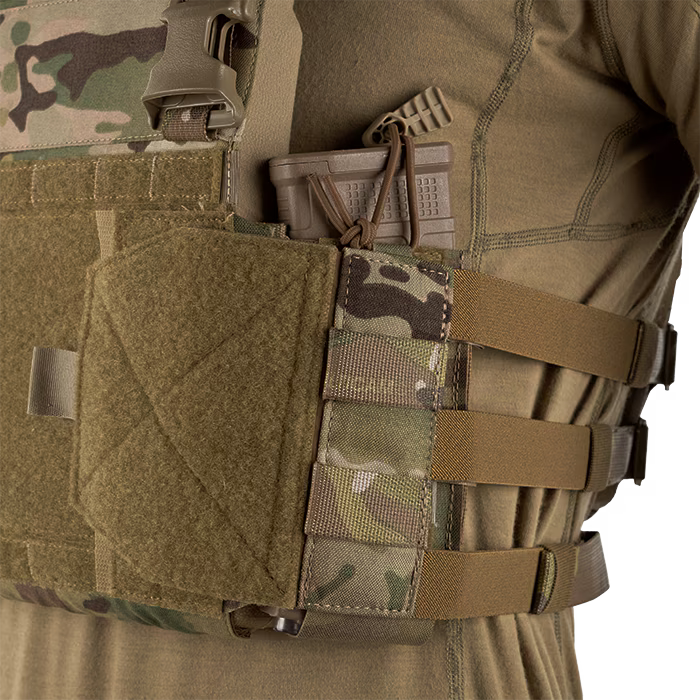 A close-up side view of an operator wearing a tactical vest equipped with the MultiCam LPV Side Radio Pouch. The pouch securely holds a brown rifle magazine, demonstrating how the adjustable bottom attachments enhance retention during active movement.