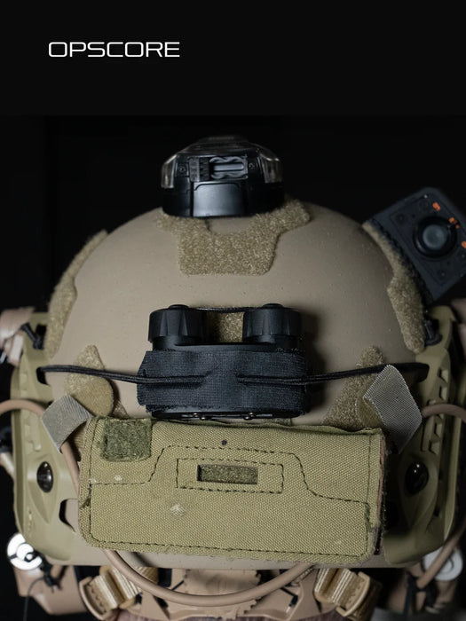 the image shows a product model wearing a ranger green or sage team ops-core helmet that has the nocturn industries mini bat pack in the black version that is attached on the helmet using the velcro backing of the battery pack and secured with the bungee/shock cored through the built in retention loops and is anchored to the helmet's rear ARC rail slots.
