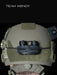 the image shows a product model wearing a ranger green or sage team wendy helmet that has the nocturn industries mini bat pack in the black version that is attached on the helmet using the velcro backing of the battery pack and secured with the bungee/shock cored through the built in retention loops and is anchored to the helmet's rear ARC rail slots.