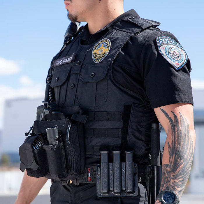Officer Garro fully equipped in the safe life defense tactical uniform shirt carrier, showing the vest supporting a full operational loadout including body camera, radio, and duty gear without compromising professional appearance.