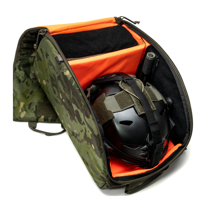 A partially open helmet bag military style in a lush Multicam Tropic pattern, displaying a black tactical bump helmet resting securely inside the vibrant orange padded compartment alongside a stored flashlight.
