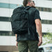 A person walking down a city street wearing the Vertx Gamut 32L Backpack, which features a discreet, low-profile design ideal for grey man operations.