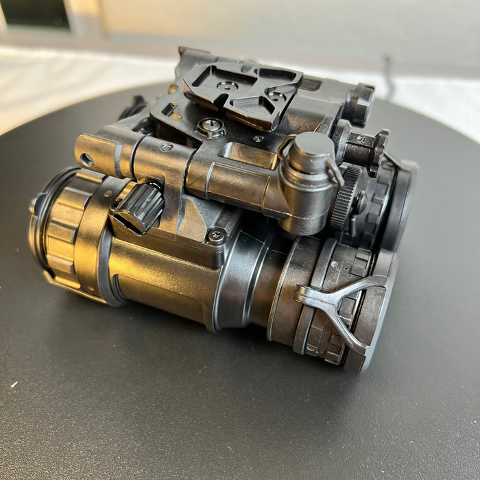 A left-side view of the pvs-31 night vision device shows the external power port prominently in the foreground, with the objective lenses securely covered by protective caps to safeguard the high-performance tubes.