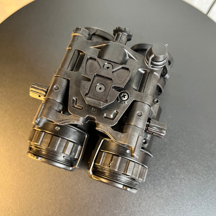 A top rear view of the pvs 31 night vision goggles features the secure dovetail mount in the foreground and the objective lenses in the background plane, showcasing the lightweight articulating housing designed to prevent neck fatigue for operators during long missions.