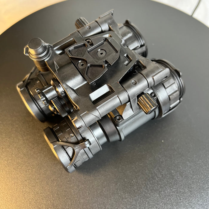 An aerial view of the pvs 31d night vision binoculars displays the top-mounted dovetail interface and the lightweight articulating housing designed to minimize operator fatigue during extended missions.