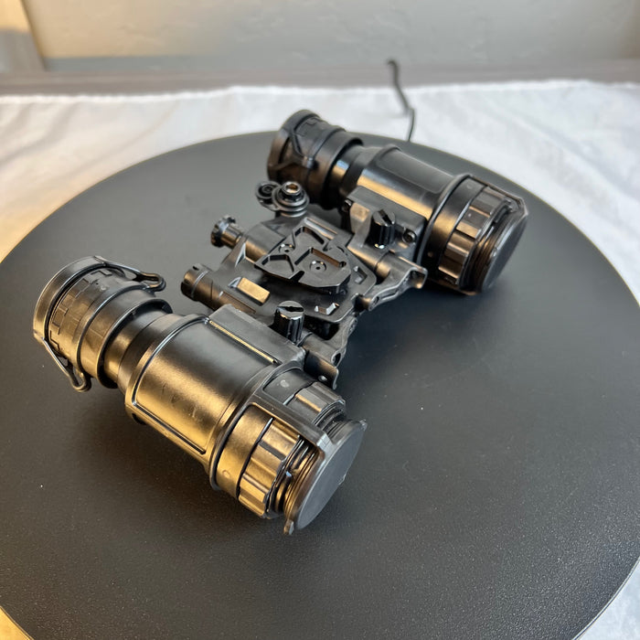 A detailed rear left-side view of the pvs 31d night vision binoculars shows the independently articulated optical pods in an open position , revealing the adjustable diopter lenses and the rugged thermoplastic housing designed for military-grade durability.