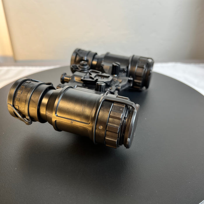 A side left view of the pvs 31d night vision goggles shows the articulating housing in an open position, with protective caps and eyecups closed on both the diopter and objective lenses to safeguard the Gen 3 white phosphor thin-filmed tubes.