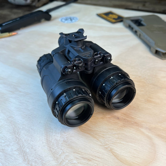 A right-angled rear perspective of the nocturn katana night vision binocular, clearly showing the ocular pieces near the viewer and the exposed objective lenses at the front without protective caps.