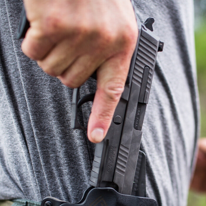 A shooter actively draws a P229 Legion Compact pistol from a holster, highlighting the accessible grip and smooth draw stroke for rapid deployment.
