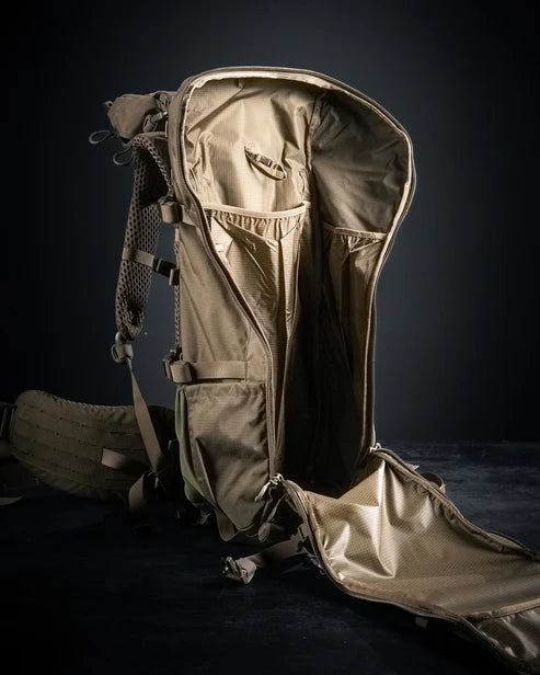 A wide-angle shot of the Eberlestock 75L Backpack fully opened, showing the massive internal capacity of the 4,500 cubic inch main compartment packed with multi-day hunting gear and bulky cold-weather layers.