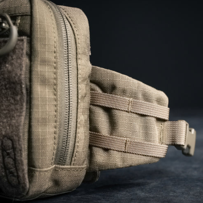 A side profile close-up of an olive green tactical bag, showing the reinforced nylon straps and side molle attachment points used for securing additional gear.