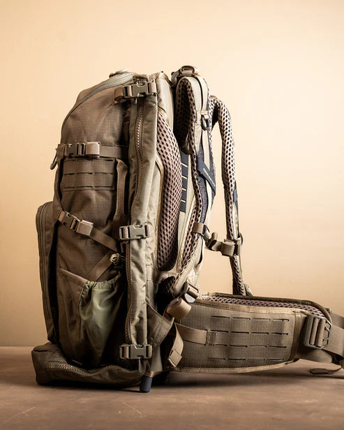 A detailed left-side profile shot of the Spectre Pack Eberlestock, highlighting the thick padding on the ergonomic shoulder straps and the heavy-duty hip belt designed for superior load distribution.