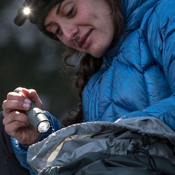 woman in blue jacket using the surefire g2x pro to search inside her pack