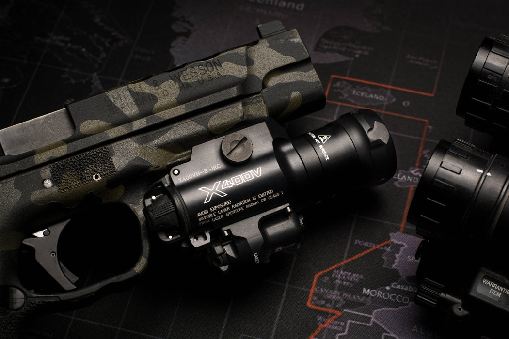 A high-resolution hero shot of the SureFire X400VH Masterfire WeaponLight positioned at an angle to showcase the clear TIR lens, the top-mounted laser adjustment screws, and the specialized cam-slotted bezel that integrates with the MasterFire holster.