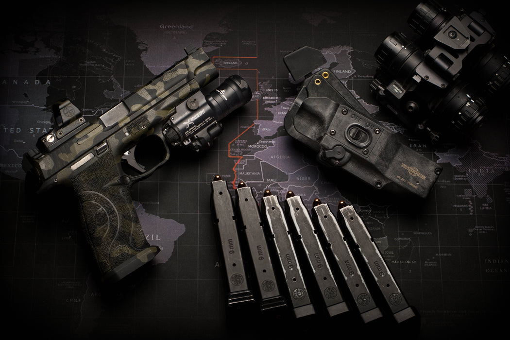 A comprehensive tactical loadout featuring the SureFire X400VH Vampire next to a MasterFire holster, several pistol magazines, and a night vision monocular to show the complete gear ecosystem required for low-light operations.