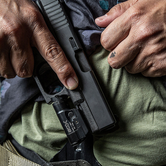 operative about to holster handgun with black surefire xc20-b weaponlight