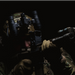 A tactical operator aiming a rifle through the DOT EHS-1, demonstrating how the tall integrated mount acts as a heads-up shooting posture optic to keep the user's head comfortably elevated during engagements.