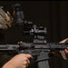Tactical operator aiming through an Infitac IOL25 Thermal Sight mounted on an AR-15 rifle.