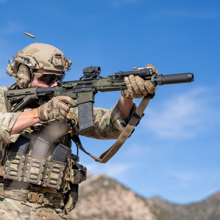 A tactical shooter engages targets at the range, keeping their weapon setup compact with an M640T Turbo Scout Light Pro mounted low on the side of the rifle.