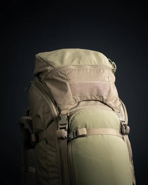 A detailed top-down shot of the Eberlestock Brute 4500 Military Pack in military green, showing the heavy-duty haul handle and the weather-resistant lid that protects the 75-liter main compartment from the elements.