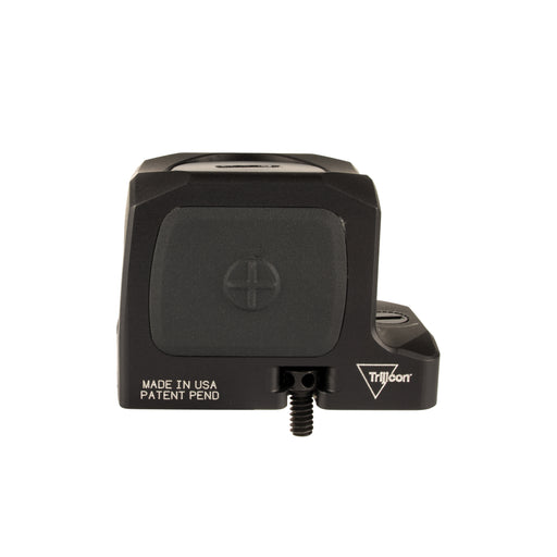 a sideview product photo of the Trijicon RCR Red Dot Sight against a plain white background and prominently featured at the front-left, reflecting a dramatic green and orange dichroic coating and showing small white laser-engraved markings are visible along the base on the right side: 'MADE IN USA PATENT PEND', with the small Trijicon 'Tri' triangle logo above it.
