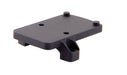 a product image of the trijicon rmr footprint mount in  back isometric view featuring a small, flat, rectangular platform featuring four distinct protrusions that are two round recoil pins and two thread screw holes and in the color black.