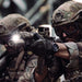 two members of a special forces unit are shown aiming rifles equipped with surefire scout light pro dual fuel, wearing tactical gear and helmets in what appears to be a training or operational environment