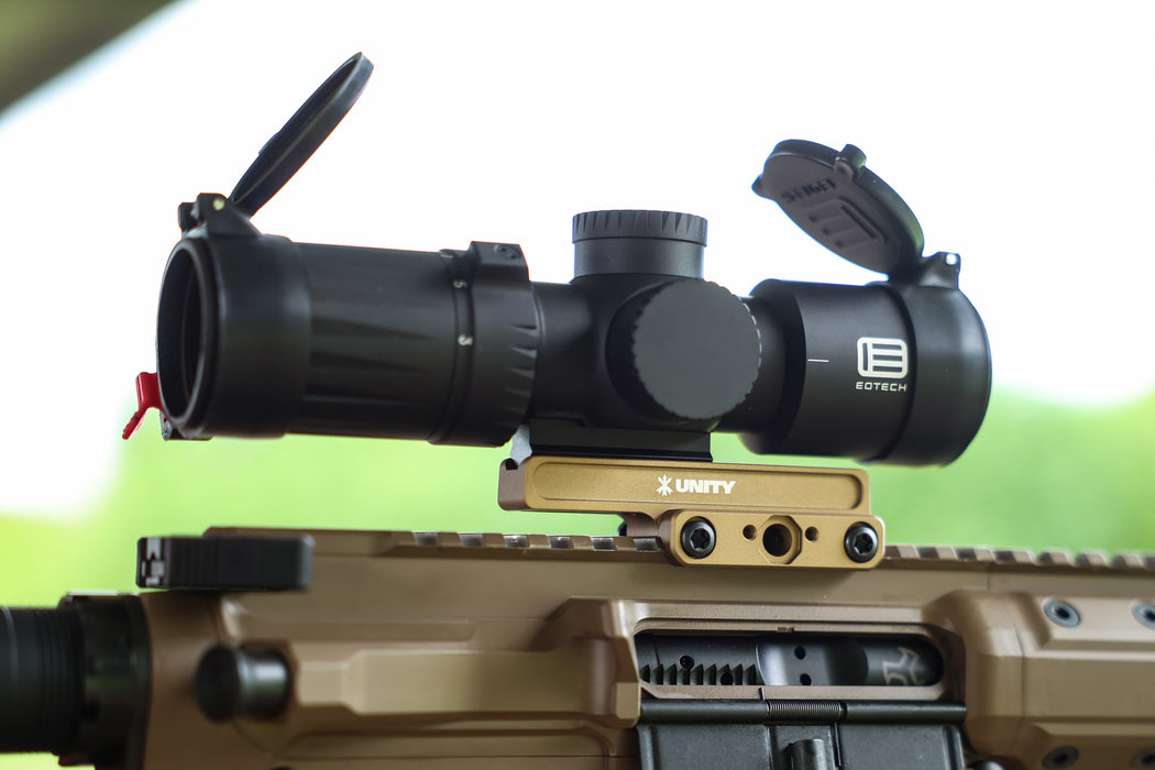 An isometric rear view of a Cobalt Kinetics AR-15 in Flat Dark Earth, displaying the FDE Unity Tactical FAST Kickr securing an EOTECH Vudu scope, illustrating the shooter's perspective and the mount's streamlined alignment.