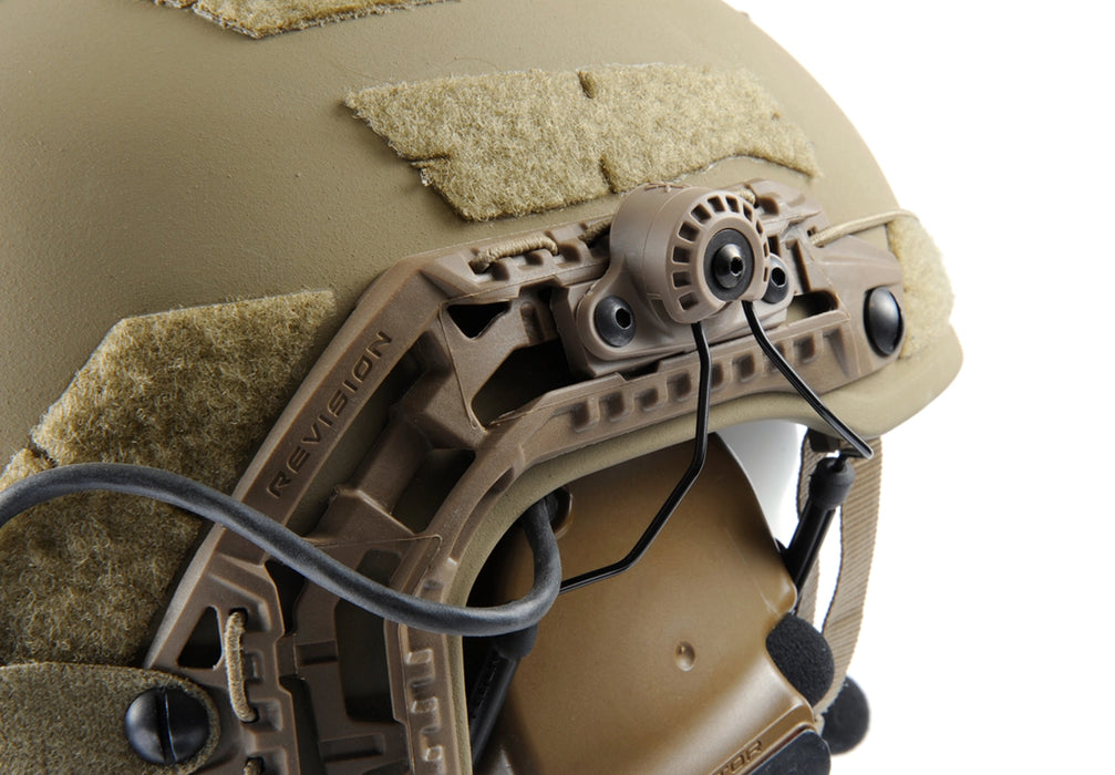 A close-up view of the coyote brown unity tactical mark securely mounting a 3M Peltor ComTac V headset to the side rails of a coyote brown Galvion Revision Caiman ballistic helmet, illustrating how the high-impact polymer body maintains a low profile.