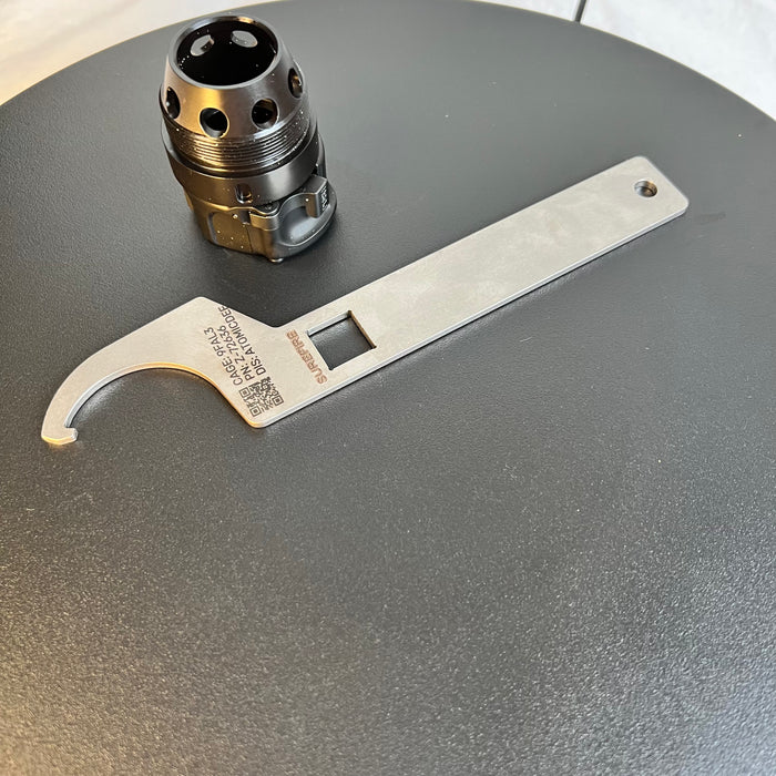 Upper view of the SureFire Spanner Tool alongside the SureFire Hub, showing the CAGE Code and Atomic Defense distributor markings.