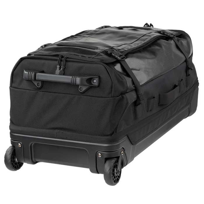 A rear photograph focuses on the bottom of the Vertx RLT 100L Duffel Roller, showing the heavy-duty molded pull handle in the foreground and the rugged, shock-absorbing 84mm wheel system built for rough terrain.