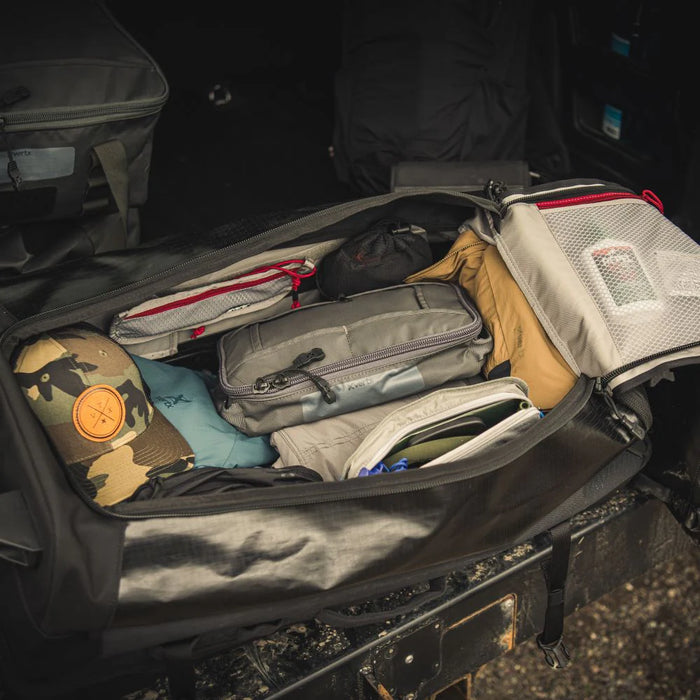 A top-down product photograph shows the main compartment of the Vertx Road Less Traveled 100L Duffel Bag fully opened to demonstrate its massive 100-liter storage capacity, packed with tactical pouches and gear organized against the light-colored interior lining.