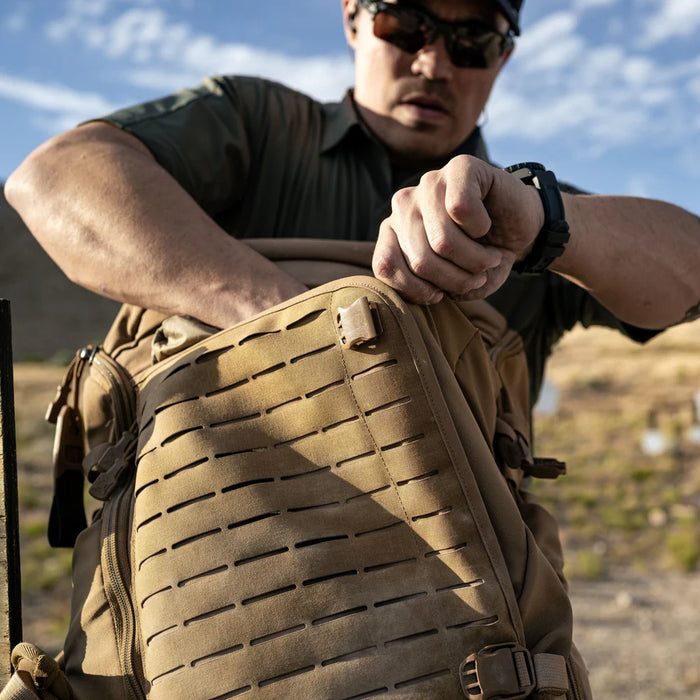 A shooter opening the expandable front pocket of the Vertx Siege 35L Tactical Backpack, demonstrating quick access to essential mission gear stored inside.